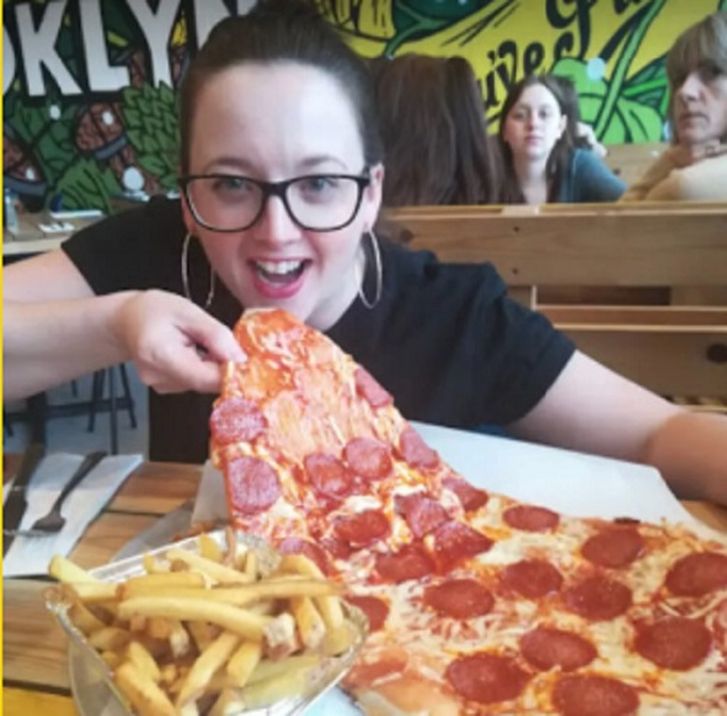 Девушка ест огромную пиццу